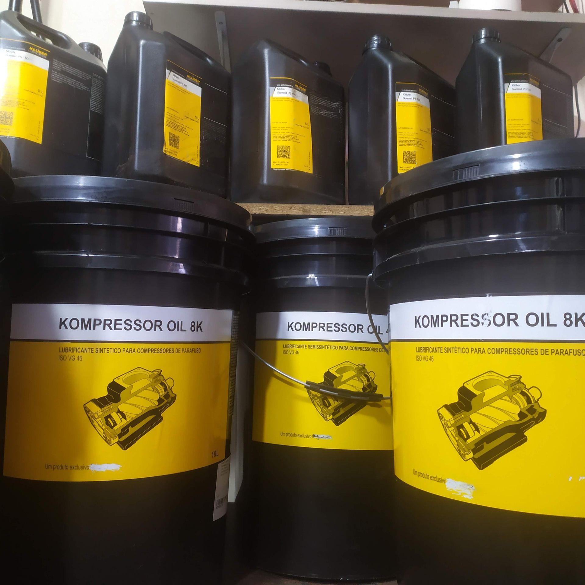 Black containers and barrels of Kompressor Oil 8K with yellow labels on a shelf.